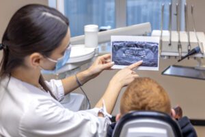 Young female dentist showing a patient a dental x-ray. Dentistry concept. High quality photo. Dentist at work. Dentist and patient.